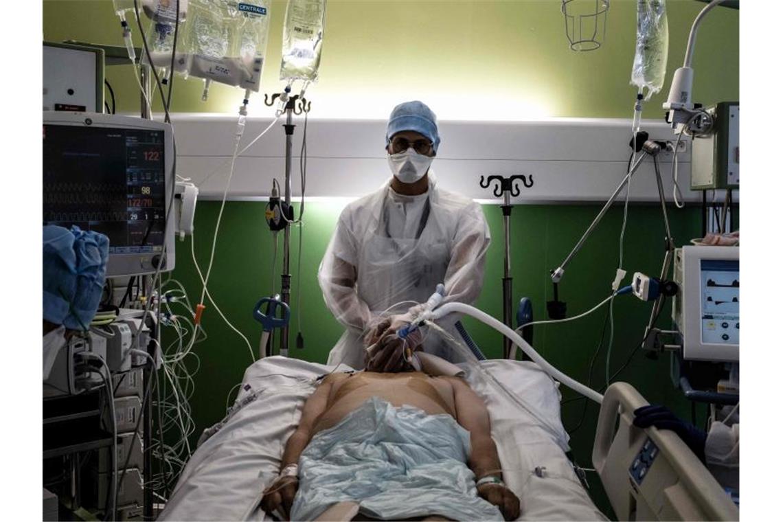 Frankreich: Impfpflicht gilt nun für bestimmte Berufsgruppen Ein medizinischer Angestellter (M) kümmert sich auf der Intensivstation eines Krankenhauses in Pierre-Benite um einen Corona-Patienten. Foto: Jeff Pachoud/AFP/dpa