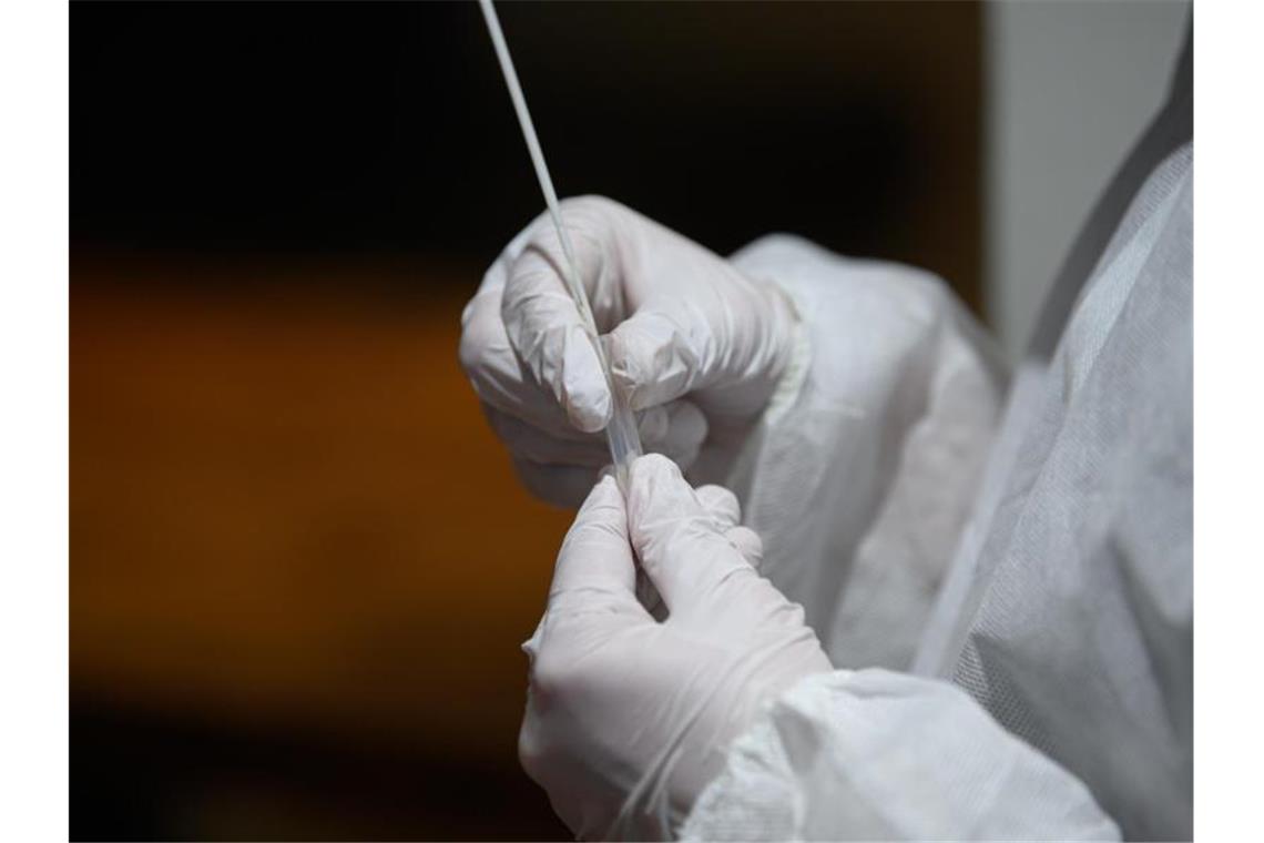 Ein medizinischer Mitarbeiter hält einen Tupfer für einen Abstrich für einen Corona-Schnelltest in der Hand. Foto: Robert Michael/dpa-Zentralbild/ZB/Symbolbild