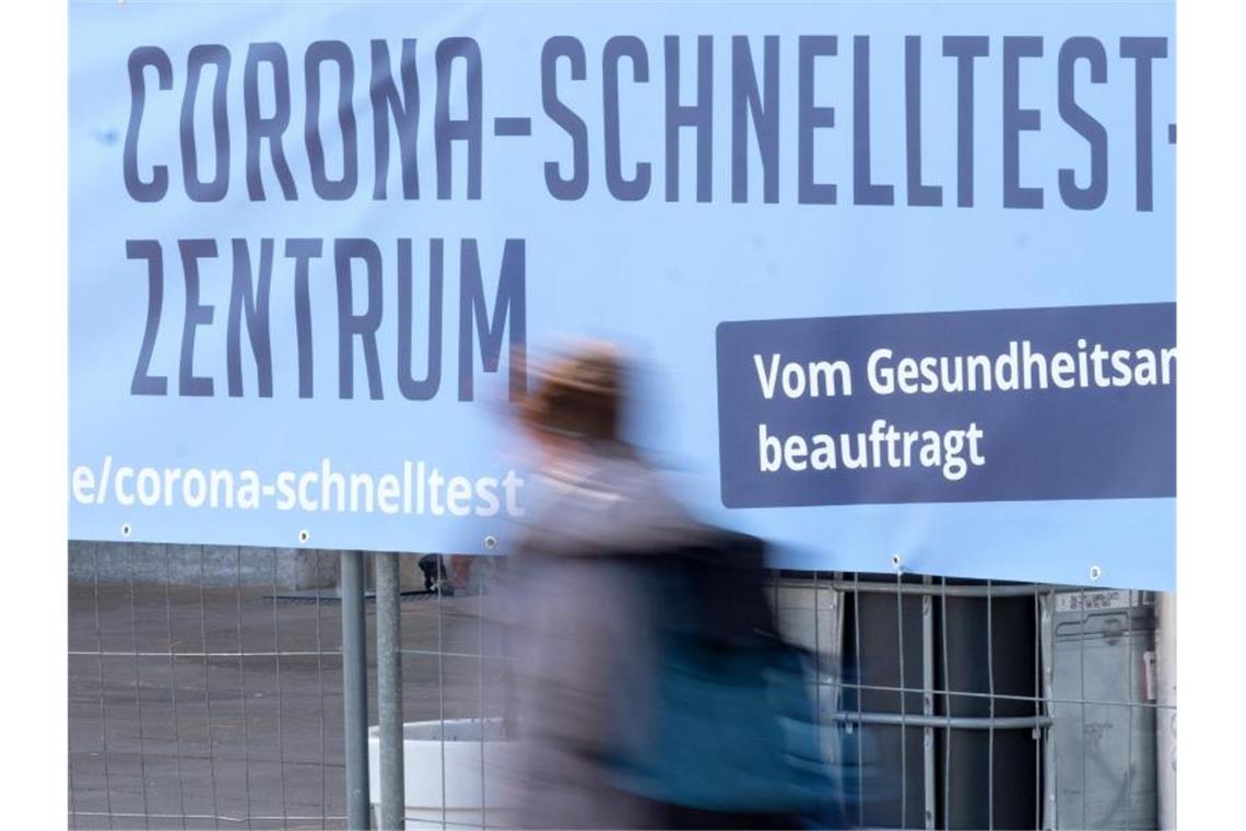 Ein Mensch geht an einem Hinweisschild für ein neues großes Schnelltest-Zentrum auf dem Schlossplatz vorbei. Foto: Bernd Weißbrod/dpa