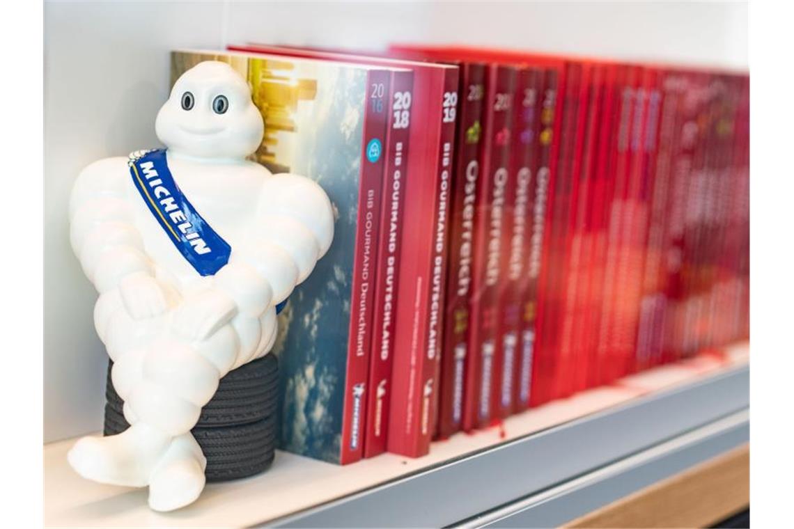 „Guide Michelin“: Neue Sterne am Gourmet-Himmel Ein Michelin-Männchen und Guide Michelins verschiedener Jahrgänge stehen im Regal. Foto: Frank Rumpenhorst/dpa