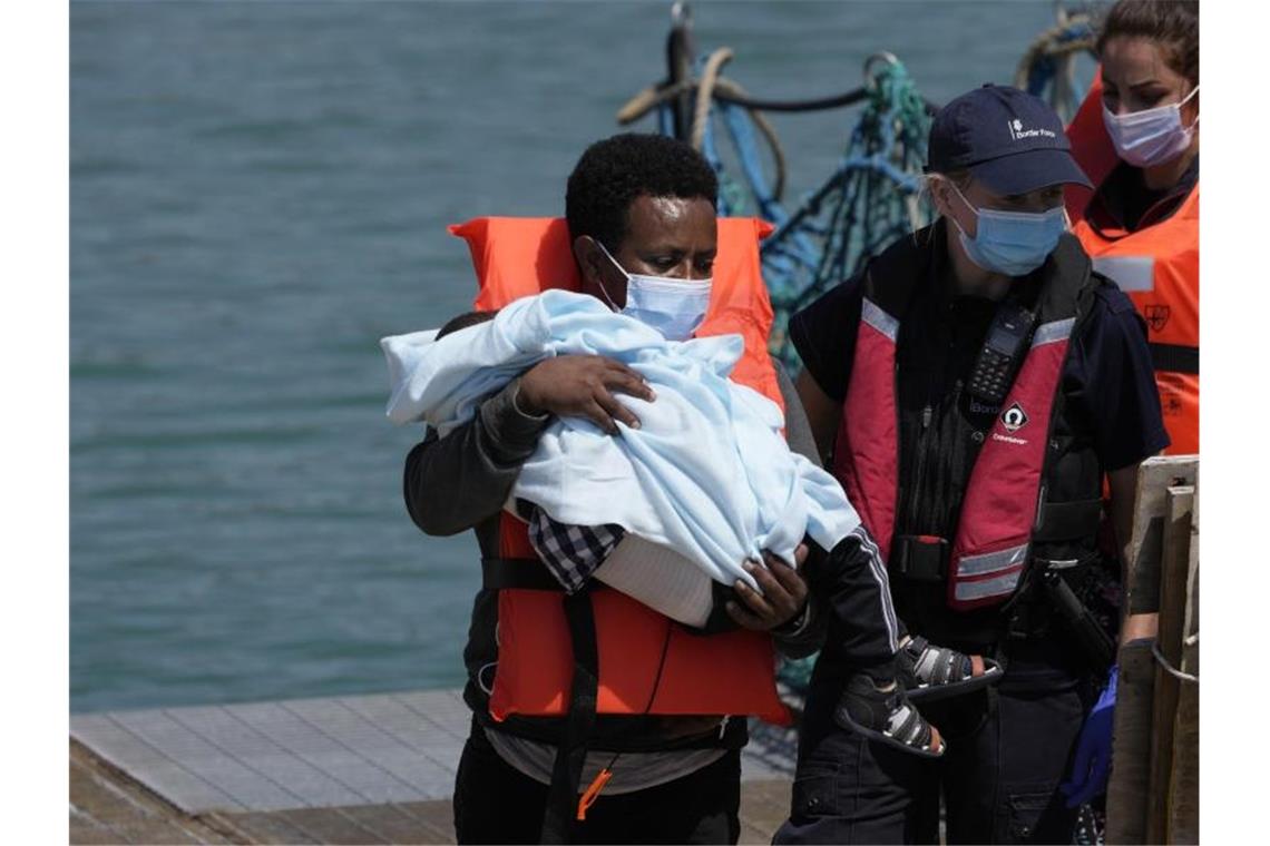 Ein Migrant hält ein Kind im Arm, während er im Hafen von Dover ankommt, nachdem er im Kanal von britischen Grenzbeamten aufgegriffen wurde. Foto: Matt Dunham/AP/dpa