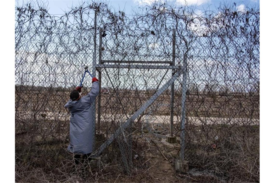 Ein Migrant versucht, an der türkisch-griechischen Grenze bei Pazarkule mit einer Drahtschere den Zaun durchzuschneiden. Foto: Yasin Akgul/dpa
