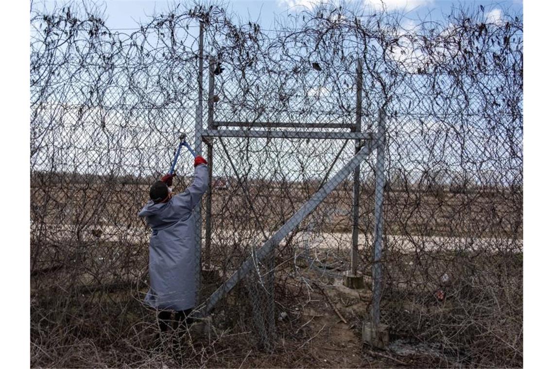 Ein Migrant versucht an der türkisch-griechischen Grenze, mit einer Drahtschere den Zaun durchzuschneiden. Foto: Yasin Akgul/dpa