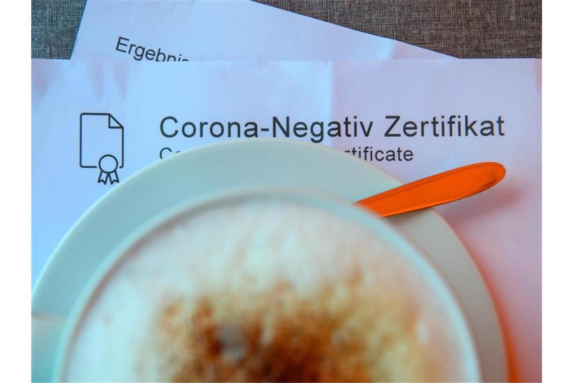 Kontaktdaten: Gastgewerbe fordert Ende der Sammelpflicht Ein Milchkaffee steht in einem Café auf einem Tisch auf einem Corona-Negativ Zertifikat. Foto: Klaus-Dietmar Gabbert/dpa-Zentralbild/dpa/Symbolbild