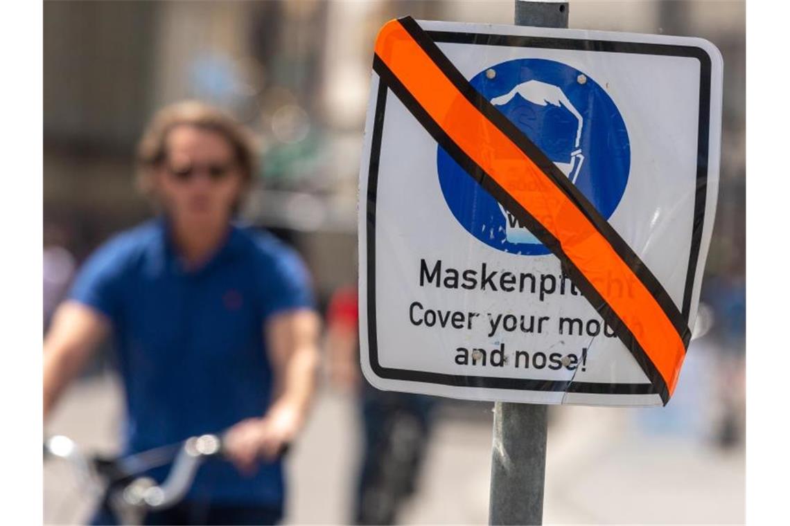 Ein mit orangen Klebeband durchgestrichenes Schild steht in der Münchner Innenstadt am Straßenrand. Die weitgehende Aufhebung der Maskenpflicht in Dänemark befeuert auch in Deutschland die Diskussion über den Sinn des Mund-Nasen-Schutzes. Foto: Peter Kneffel/dpa