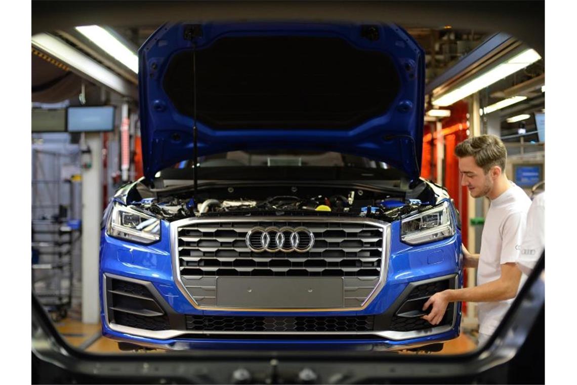 Ein Mitarbeiter bringt an einem Fließband im Audi-Werk das Frontende an einem Audi an. Foto: dpa