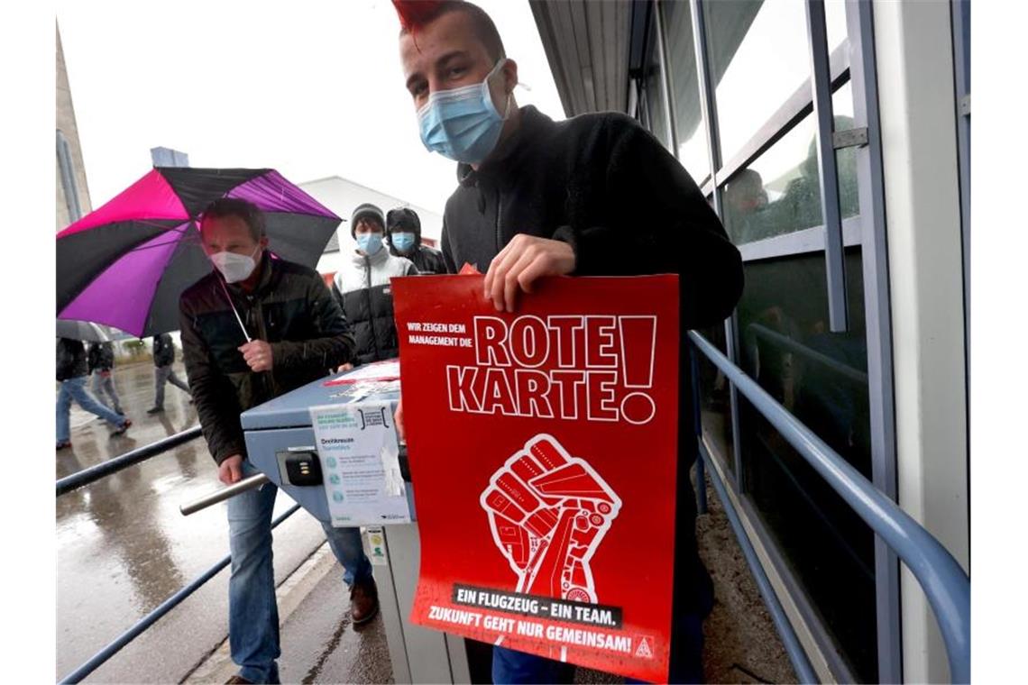 Airbus-Belegschaft im Konfliktmodus - Gegen Umbaupläne Ein Mitarbeiter der Airbus-Tochter Premium Aerotec verlässt nach einer Protestaktion mit einem Plakat, auf dem "Wir zeigen dem Management die rote Karte" zu lesen ist, das Betriebsgelände des Unternehmens. Foto: Karl-Josef Hildenbrand/dpa