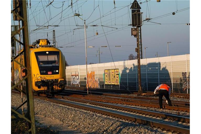 Ein Mitarbeiter der Bahn steht zwischen den Gleisen und greift nach einem Teil der Oberleitung. Foto: Christina Häußler/Einsatz-Report24/dpa