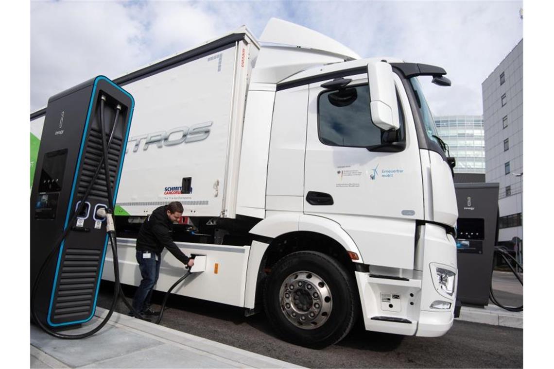 Mercedes startet Serienproduktion von E-Lkw Ein Mitarbeiter der Daimler AG steckt einen Ladestecker in einen eActros. Foto: Marijan Murat/dpa/archivbild