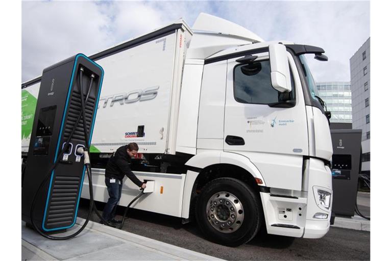 Ein Mitarbeiter der Daimler AG steckt einen Ladestecker in einen elektrisch angetriebenen Mercedes-Benz eActros. Foto: Marijan Murat/dpa