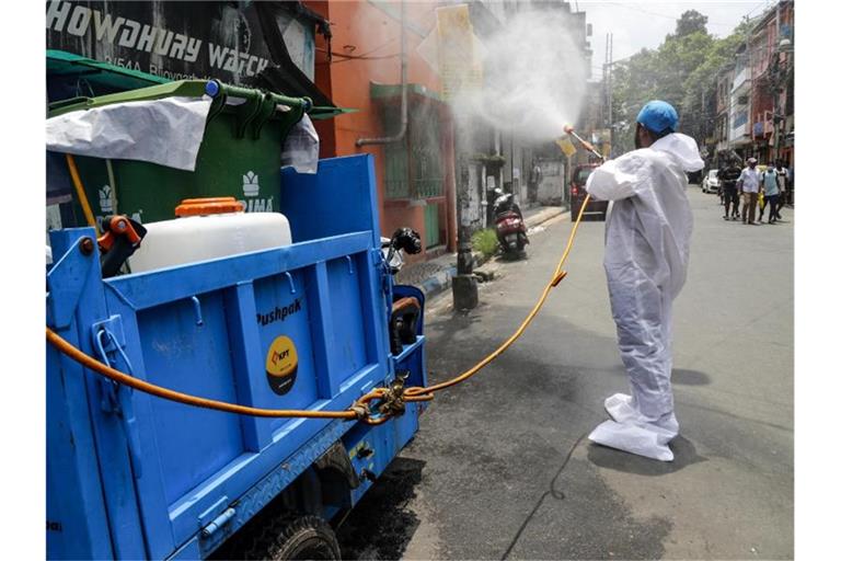 Ein Mitarbeiter der Stadt desinfiziert in Kolkata eine Straße. Ein strikter Lockdown hatte die wirtschaftlichen Aktivitäten in Indien zwischenzeitlich nahezu zum Erliegen gebracht. Foto: Bikas Das/AP/dpa