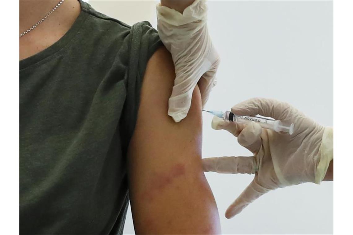 Moskau beginnt mit großangelegten Corona-Impfungen Ein Mitarbeiter des Gesundheitswesens führt in Moskau eine Impfung mit dem Corona-Impfstoff „Sputnik V“ durch. Foto: Pavel Golovkin/AP/dpa