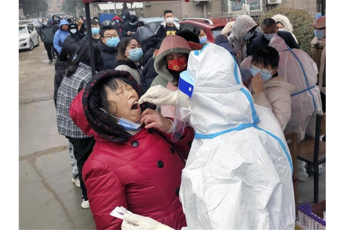 Nächste Millionenmetropole in China verhängt Lockdown Ein Mitarbeiter des Gesundheitswesens in einem Schutzanzug macht Abstriche für Corona-Tests bei Anwohnern. Foto: CHINATOPIX/AP/dpa