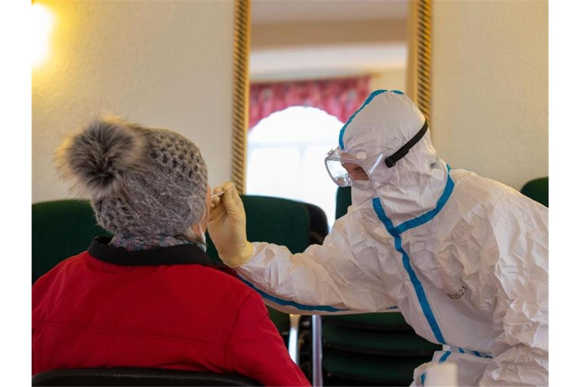 Ein Mitarbeiter des Gesundheitswesens nimmt von der einer älteren Dame einen Rachenabstrich. Foto: Daniel Schäfer/dpa-Zentralbild/dpa