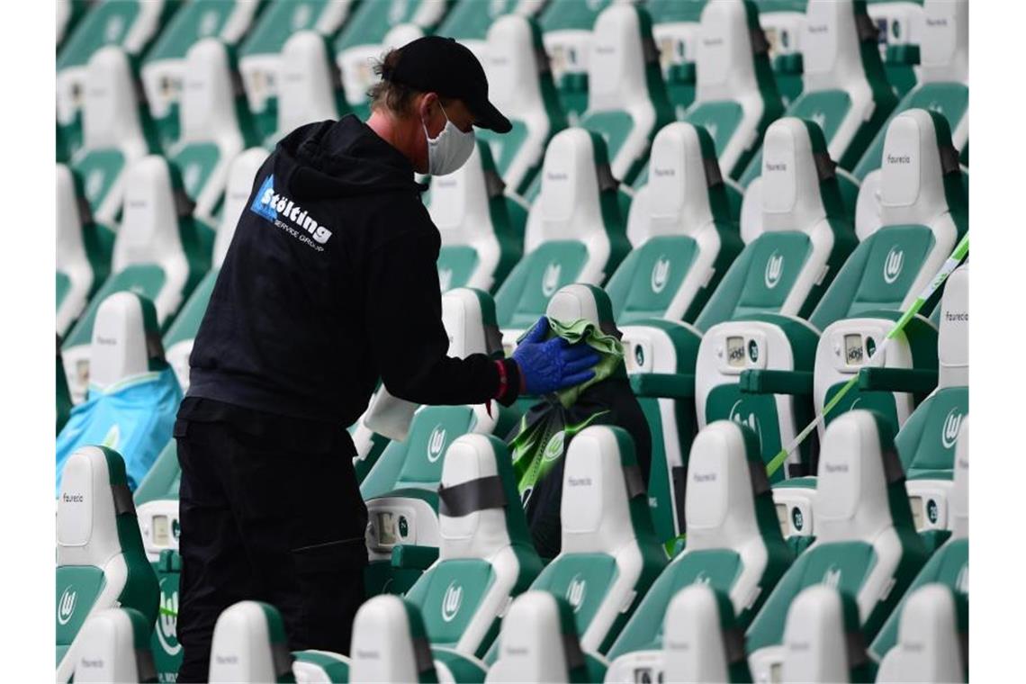 Ein Mitarbeiter desinfiziert in einem Stadion die Sitzplätze für Ersatzspieler. Foto: Swen Pförtner/dpa/Archiv/Symbolbild