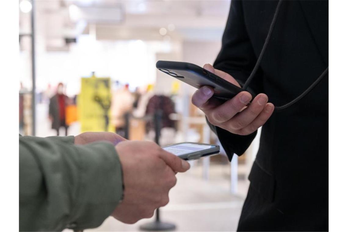 Polizei soll eventuell Impfnachweise kontrollieren dürfen Ein Mitarbeiter eines Kaufhauses kontrolliert am Eingang mit einem Smartphone die Einhaltung der 2G-Regel und den Impfnachweis einer Kundin. Foto: Bernd Weißbrod/dpa/Symbolbild