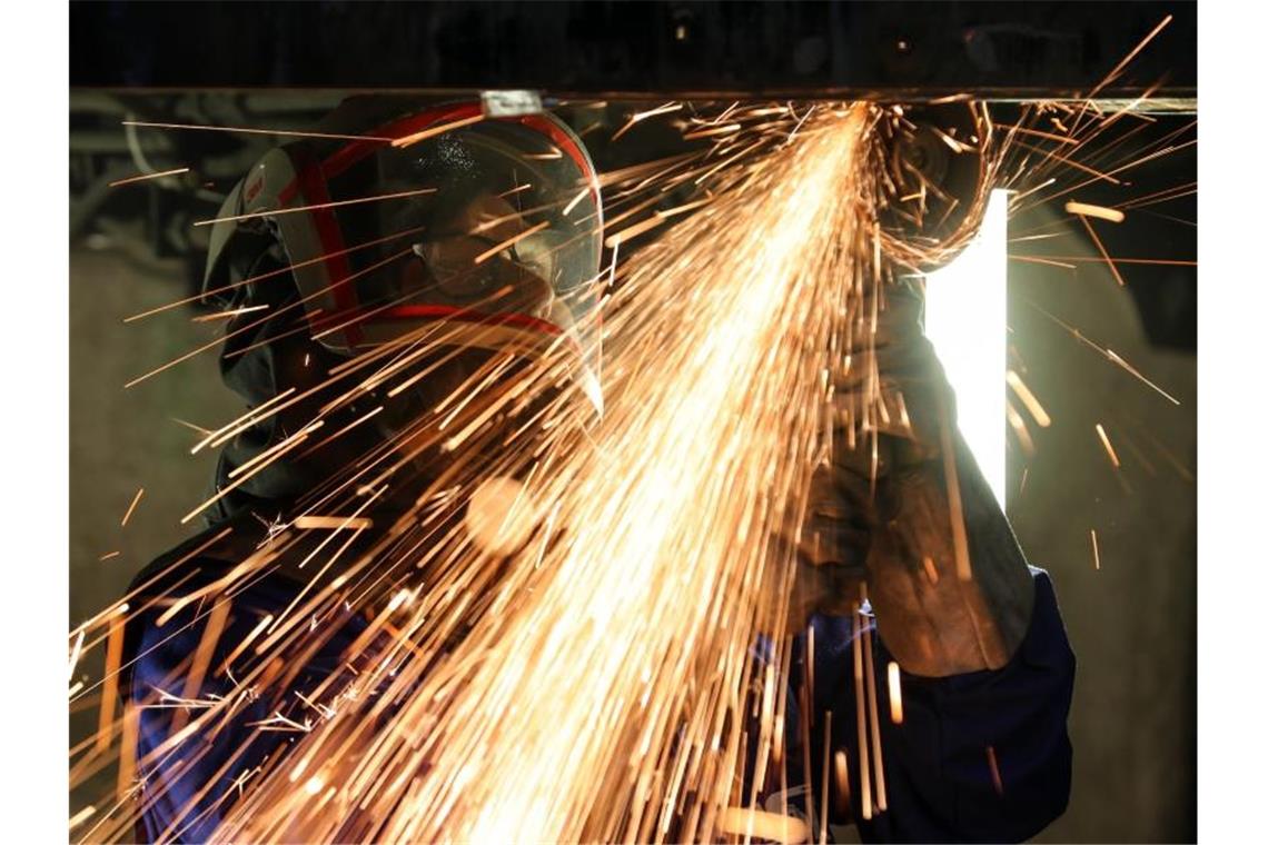 Ein Mitarbeiter eines Maschinenbauers schneidet mit einem Trennschleifer korrodierte Metallteile. Foto: Jan Woitas/dpa-Zentralbild/dpa/Symbolbild