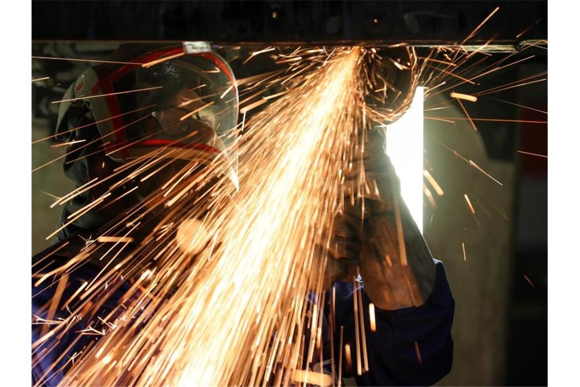Ein Mitarbeiter eines Maschinenbauers schneidet mit einem Trennschleifer korrodierte Metallteile aus dem Träger in einem Wagenkasten. Foto: Jan Woitas/dpa-Zentralbild/dpa