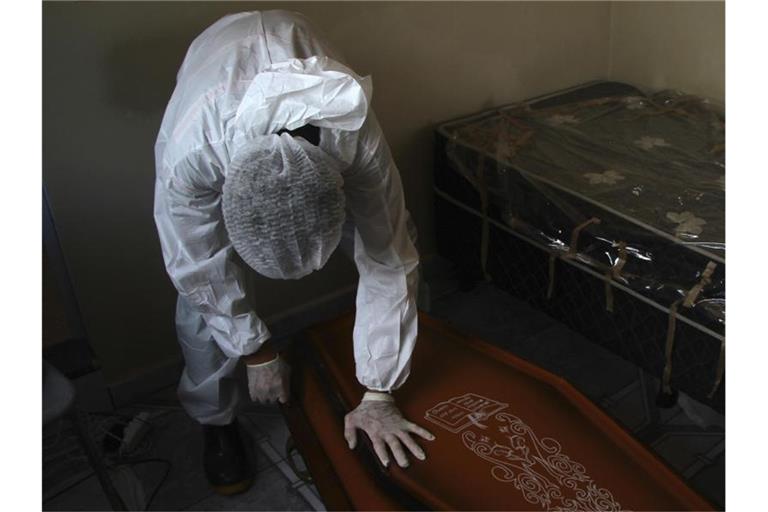 Ein Mitarbeiter eines öffentlichen Bestattungsdienstes in Manaus verschließt einen Sarg mit dem Leichnam eines Mannes, der an Komplikationen im Zusammenhang mit Covid-19 gestorben ist. Foto: Edmar Barros/AP/dpa