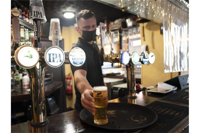 Ein Mitarbeiter eines Pubs serviert ein Bier. Trotz weitreichender Lockerungen von Corona-Regeln haben britische Pubs erneut deutlich weniger Bier verkauft als vor der Pandemie. Foto: Jon Super/AP/dpa