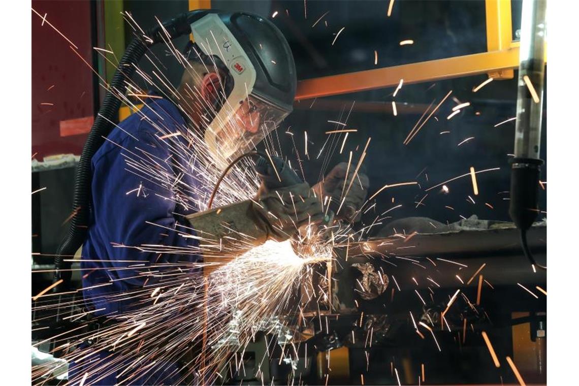 Ein Mitarbeiter eines Unternehmen im Bereich Maschinenbau schneidet mit einem Trennschleifer korrodierte Metallteile aus dem Träger eines Wagenkastens einer S-Bahn. Foto: Jan Woitas/dpa-Zentralbild/dpa