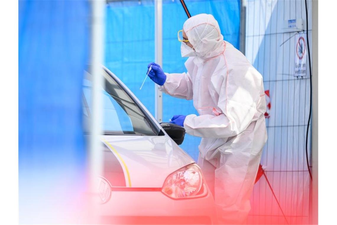 Mehr als 2000 Corona-Tote in Deutschland Ein Mitarbeiter führt in einem Corona-Abstrichzentrum einen Test durch. Foto: Sebastian Gollnow/dpa