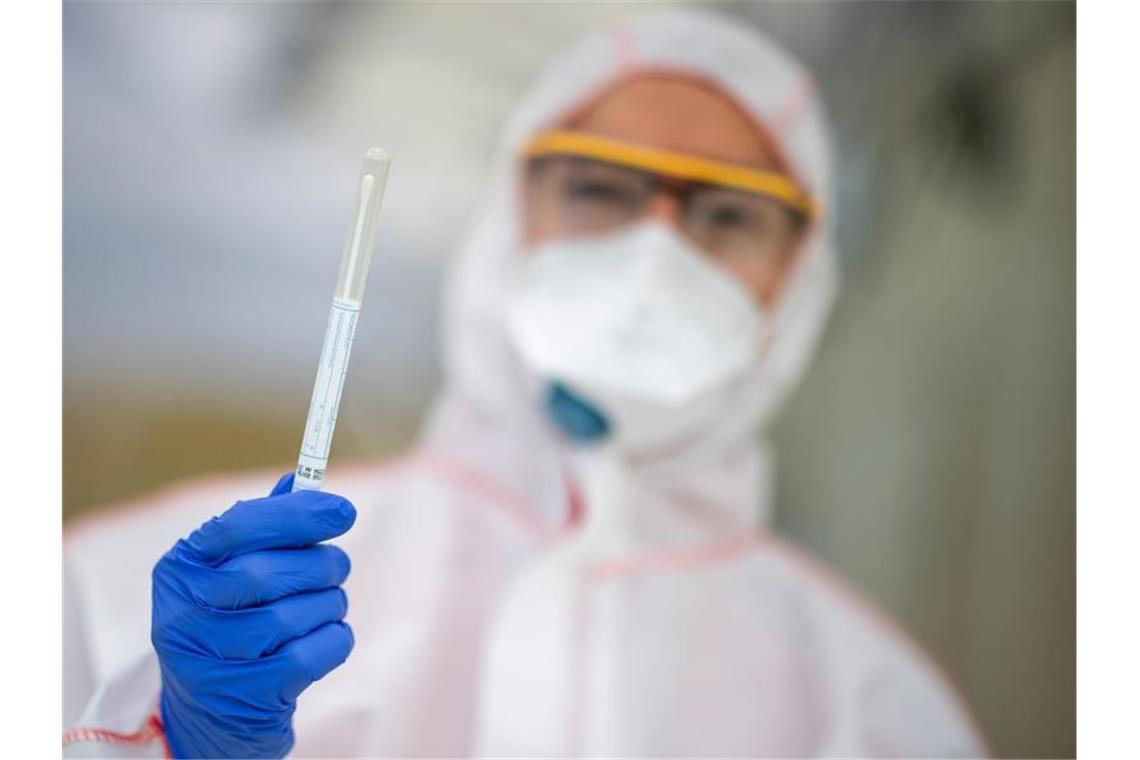 Ein Mitarbeiter hält in einem Abstrichzentrum einen Coronatest-Abstrich in der Hand. Foto: Sebastian Gollnow/dpa/Symbolbild