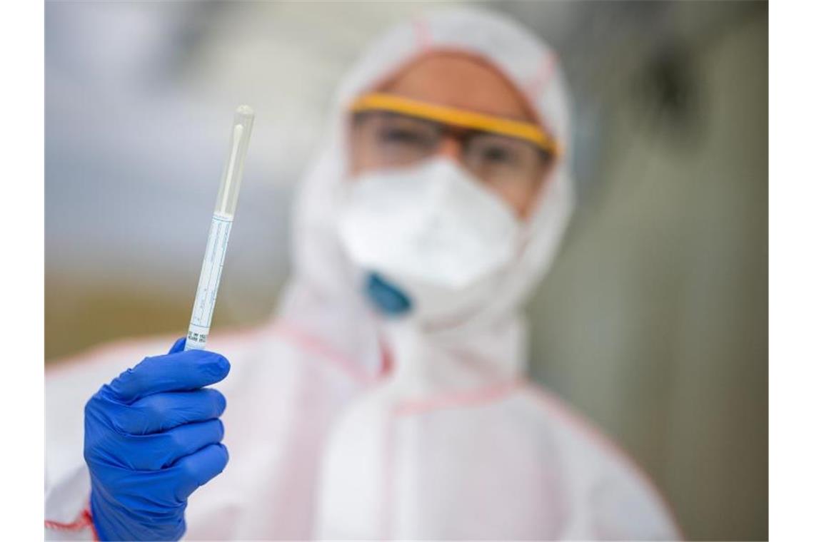 Ein Mitarbeiter hält in einem Abstrichzentrum einen Coronatest-Abstrich in der Hand. Foto: Sebastian Gollnow/dpa/Symbolbild