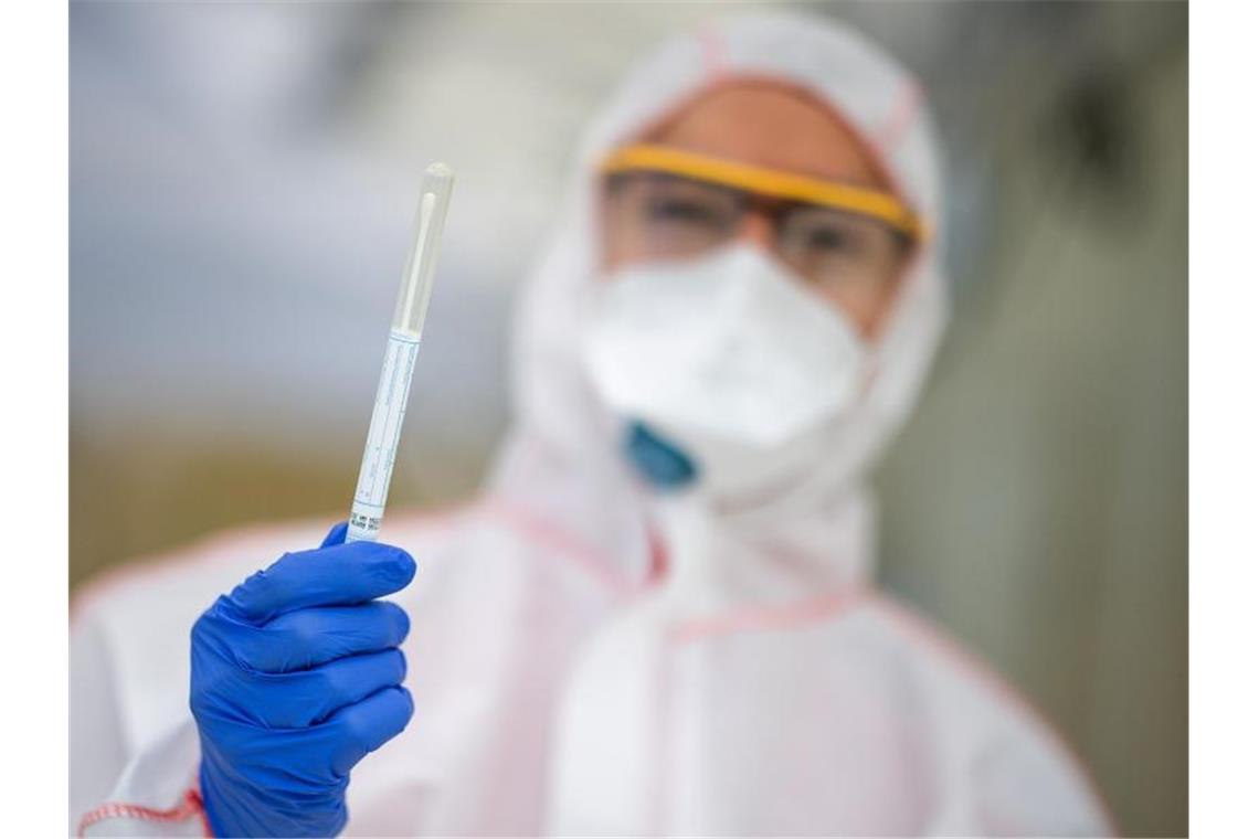 Ein Mitarbeiter hält in einem Abstrichzentrum einen Coronatest-Abstrich in der Hand. Foto: Sebastian Gollnow/dpa/Symbolbild