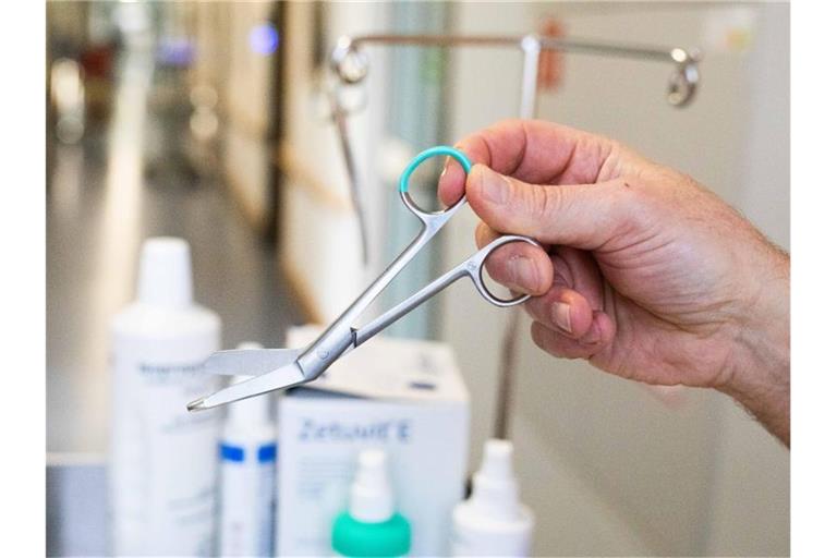 Ein Mitarbeiter hält in einer Klinik eine Schere aus nicht-wiederverwendbarem Edelstahl. Foto: Philipp von Ditfurth/dpa/Archivbild