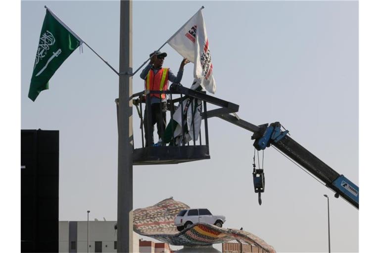 Ein Mitarbeiter hängt Flaggen an der Rennstrecke des Corniche Circuit auf: Die Formel 1 gastiert erstmals in Saudi-Arabien. Foto: Amr Nabil/AP/dpa