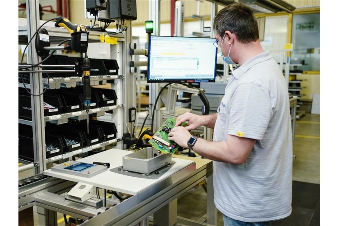 Ein Mitarbeiter montiert in einem Stammwerk in Baden-Württemberg ein Ladegerät. Foto: Uwe Anspach/dpa/Archivbild