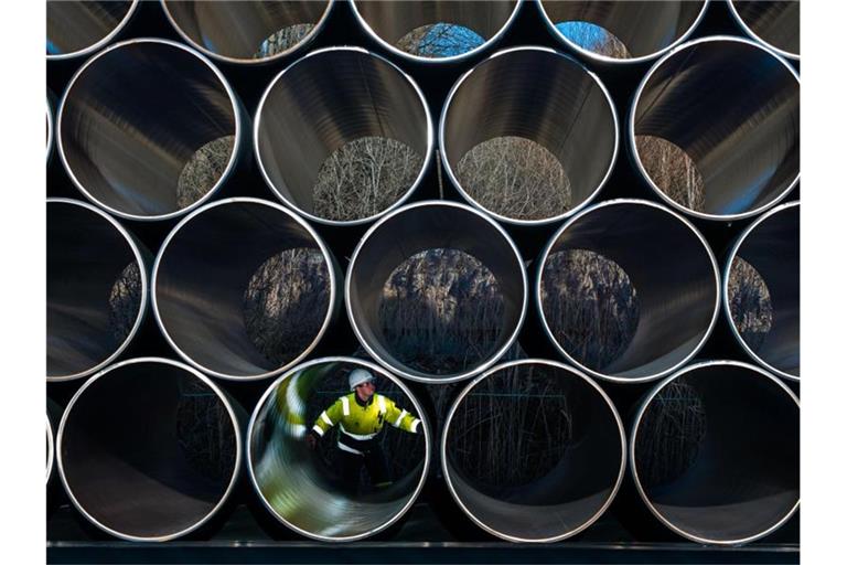 Ein Mitarbeiter prüft tonnenschwere Rohre für die zukünftige Ostsee-Erdgastrasse Nord Stream 2 auf einem Lagerplatz im Hafen. Foto: Jens Büttner/dpa-Zentralbild/dpa