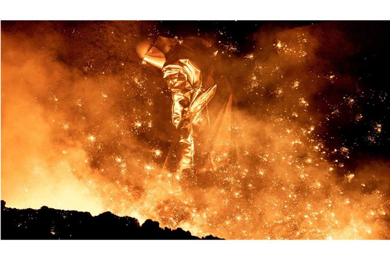 Ein Mitarbeiter reinigt in einem Stahlwerk in Salzgitter die Abstichrinne am Hochofen.