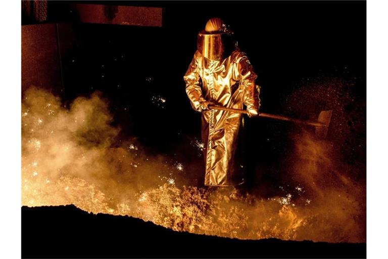 Ein Mitarbeiter schaufelt im Stahlwerk der Salzgitter AG Sand in eine Abstichrinne am Hochofen. Foto: Hauke-Christian Dittrich/dpa