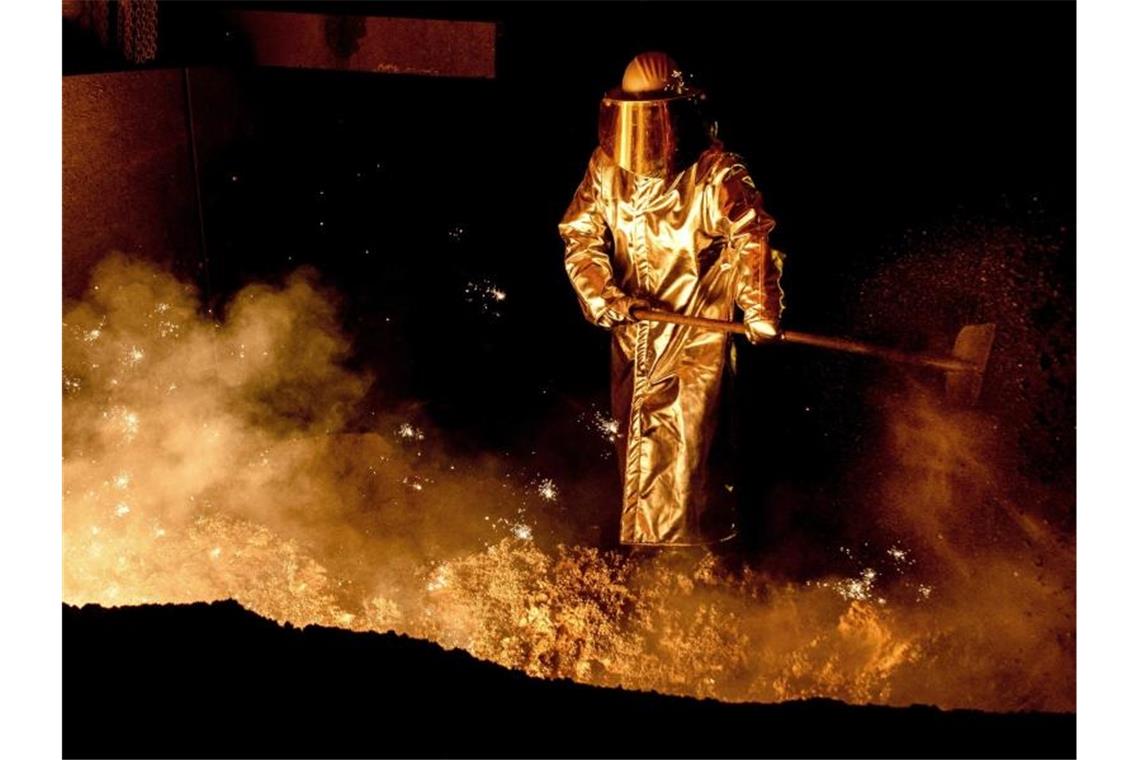 Ein Mitarbeiter schaufelt im Stahlwerk der Salzgitter AG Sand in die Abstichrinne am Hochofen. Foto: Hauke-Christian Dittrich/dpa