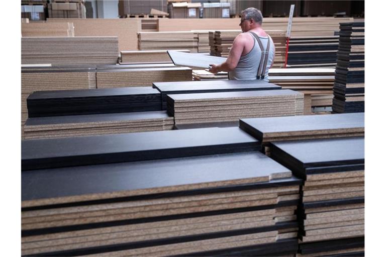Ein Mitarbeiter sortiert Möbelplatten in einem Werk in Brandenburg. Foto: Jens Büttner/dpa-Zentralbild/dpa