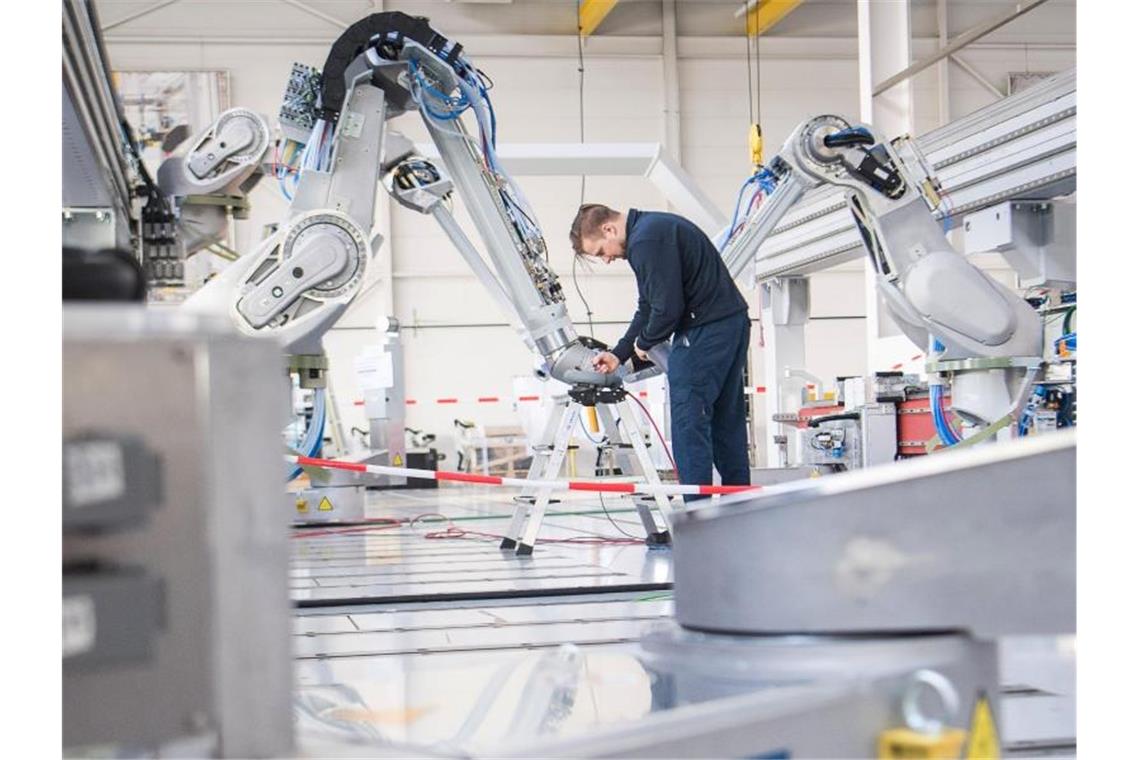 Ein Mitarbeiter testet einen Lackierroboter bei der Dürr AG. Foto: Sebastian Gollnow/dpa