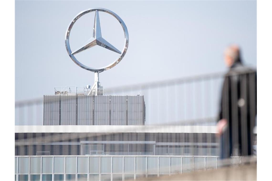 Ein Mitarbeiter von Daimler geht an einem Mercedes-Benz Werk vor einem Mercedes-Stern. Foto: Sebastian Gollnow/dpa/Symbolbild