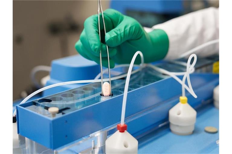 Ein Mitarbeiter von Pfizer hält eine Paxlovid-Tablette mit einer Zange. Foto: Pfizer/dpa