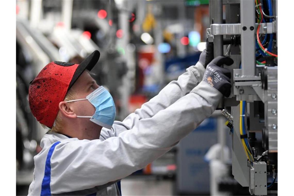 Ein Mitarbeiter von Volkswagen Sachsen arbeitet in der Montage des ID.3 im Fahrzeugwerk mit Mundschutz. Foto: Hendrik Schmidt/dpa-Zentralbild/POOL/dpa