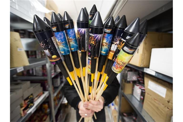 Ein Mitarbeiter von Weco, Hersteller von Feuerwerk, hält in einem Lagerraum Silvesterraketen. Foto: Christophe Gateau/dpa/Archiv