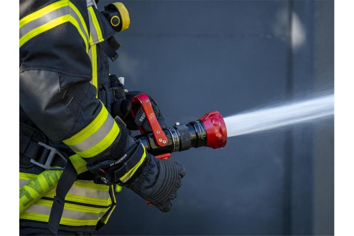 Millionenschaden bei Brand in Lackfabrik Ein Mitglied der Feuerwehr spritzt aus einem Schlauch mit Wasser. Foto: David Inderlied/dpa/Symbolbild