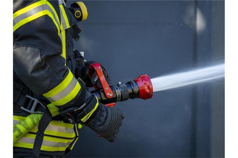 Ein Mitglied der Feuerwehr spritzt aus einem Schlauch mit Wasser. Foto: David Inderlied/dpa/Symbolbild
