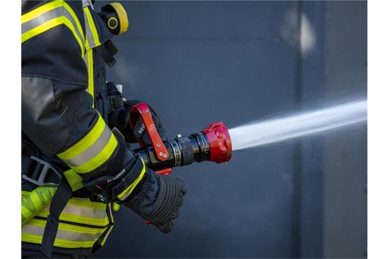Ein Mitglied der Feuerwehr spritzt aus einem Schlauch mit Wasser. Foto: David Inderlied/dpa/Symbolbild