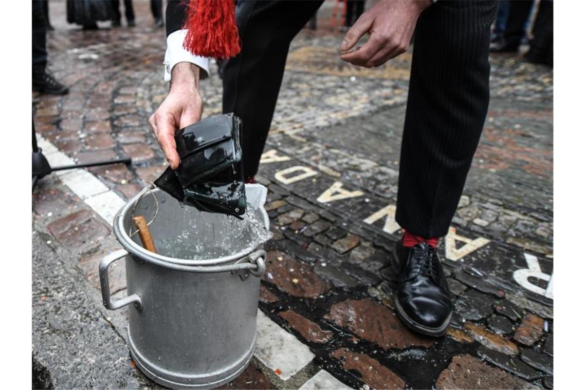 Ein Mitglied der Freiburger „Zunft der Fuhrleute“ wäscht vor dem Rathaus seinen Geldbeutel. Foto: Patrick Seeger/dpa