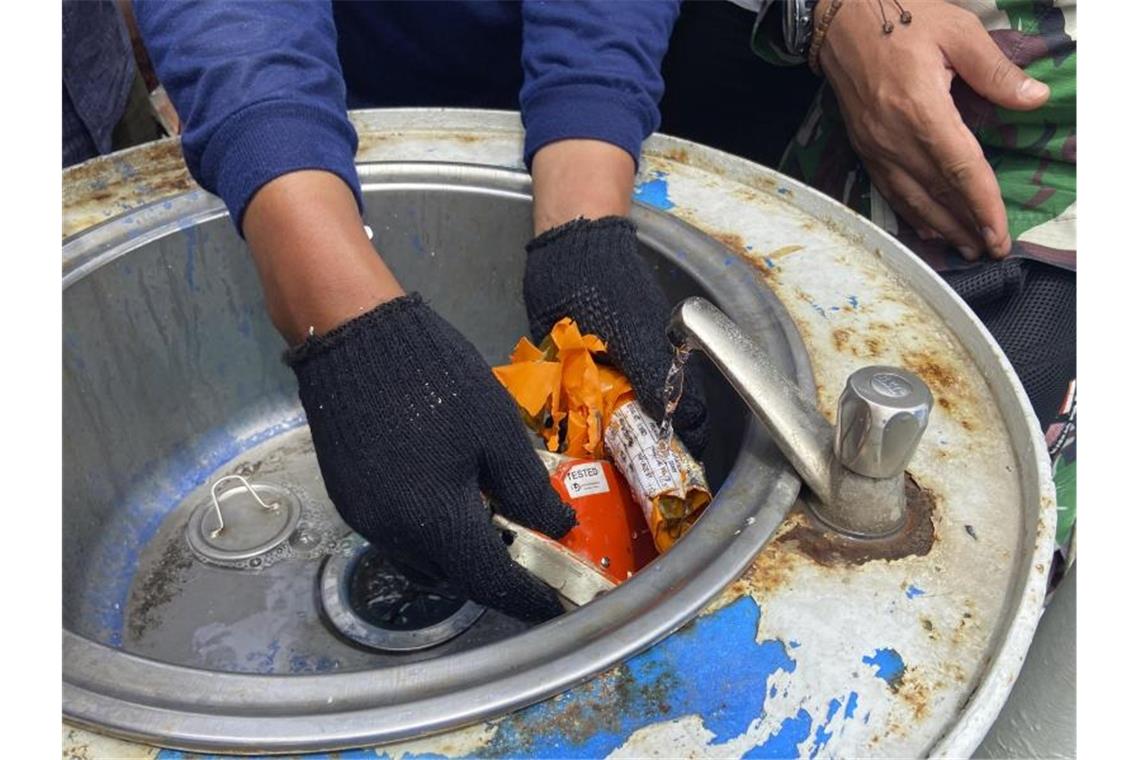 Ein Mitglied der indonesischen Marine inspiziert ein Teil des Flugdatenschreibers. Foto: Fadlan Syam/AP/dpa