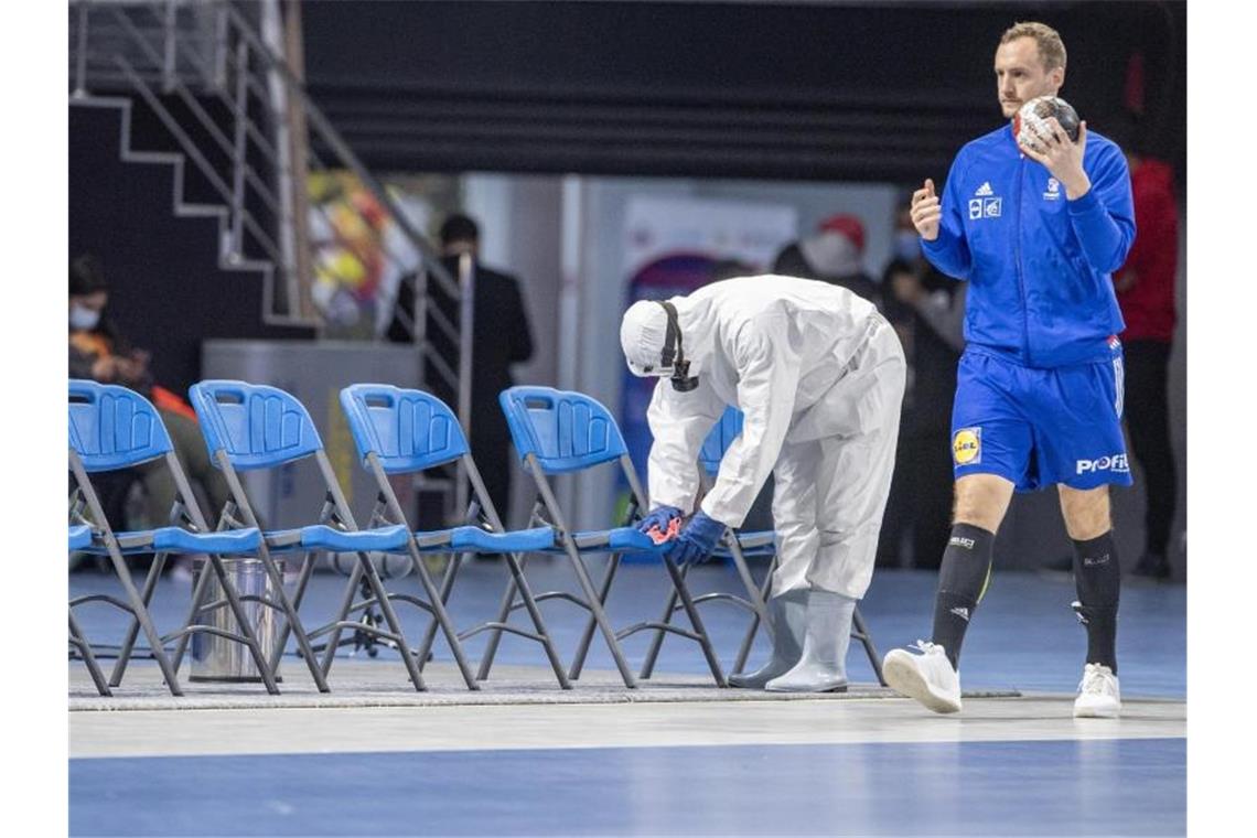 Hygiene-Experte: Kein erhöhtes Risiko für WM-Handballer Ein Mitglied des Corona-Desinfektionsteams desinfiziert Stühle vor der WM-Partie Österreich gegen Frankreich. Foto: Urs Flueeler/KEYSTONE/dpa