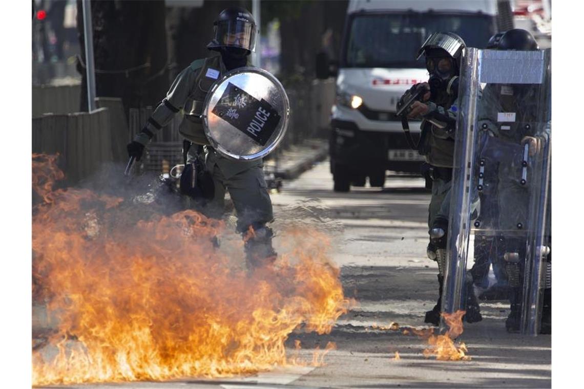 Ein Molotow-Cocktail geht vor Polizisten in Flammen auf. Foto: Ng Han Guan/AP/dpa