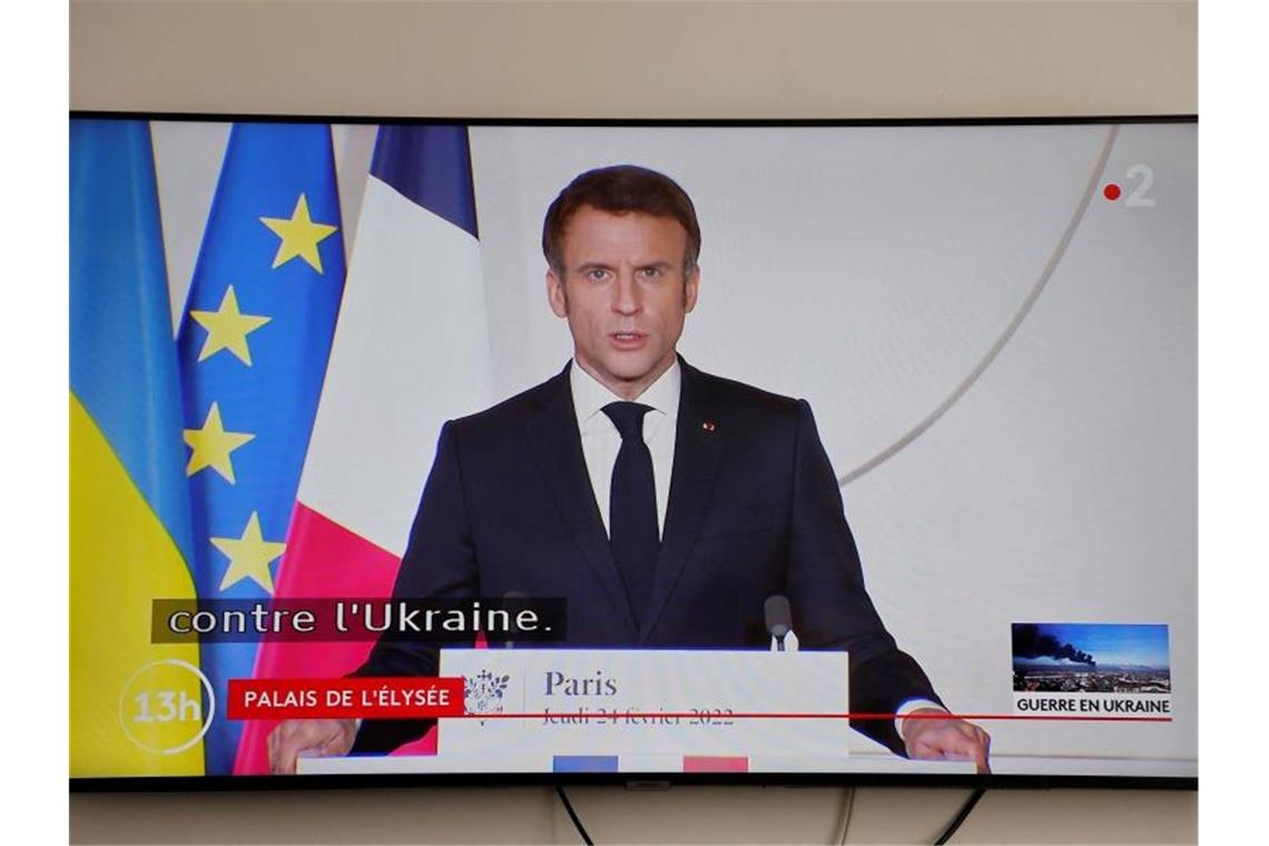 Macron über Putin-Telefonat: „Hat keine Wirkung gezeigt“ Ein Monitor überträgt die Rede des französischen Präsidenten Emmanuel Macron zur Lage in der Ukraine. Foto: Ludovic Marin/AFP/dpa